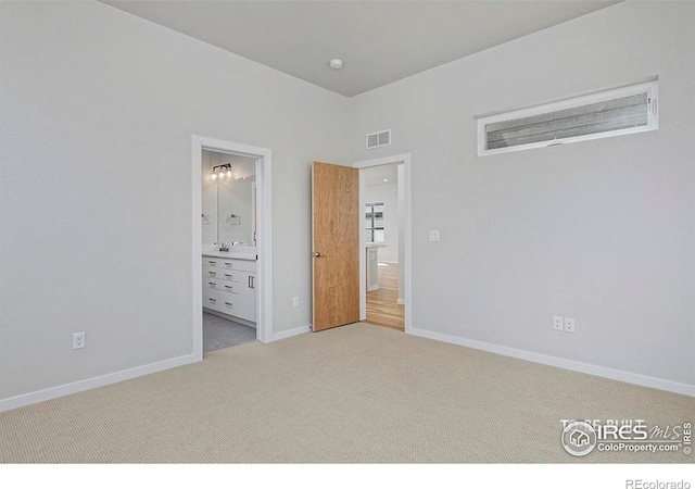 unfurnished bedroom featuring ensuite bath and light carpet