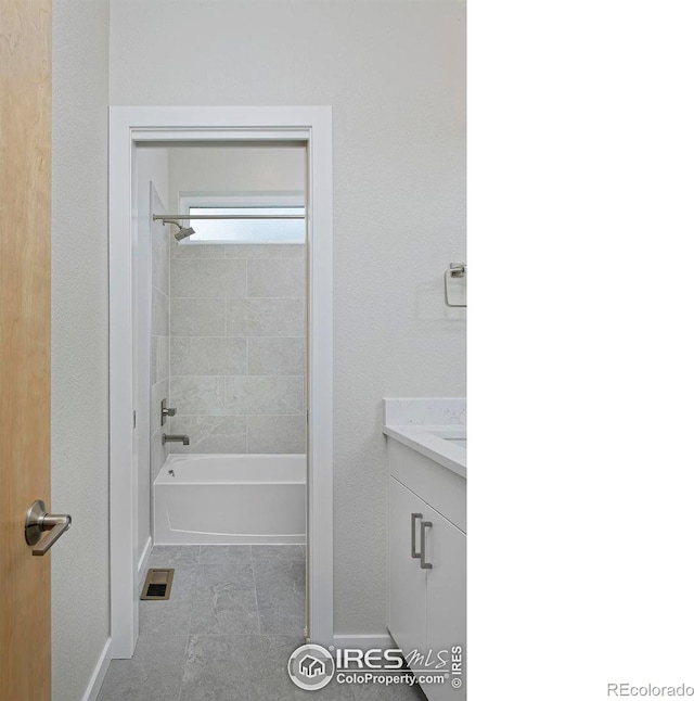 bathroom with tile patterned flooring, tiled shower / bath combo, and vanity