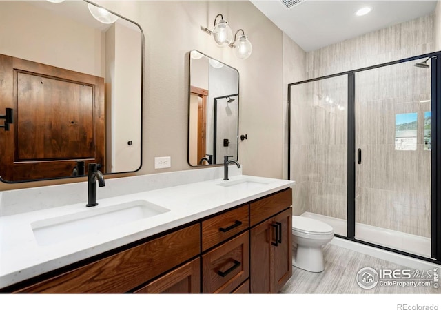 bathroom with wood-type flooring, vanity, toilet, and walk in shower