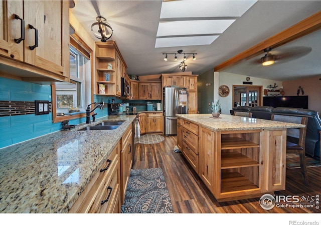 kitchen featuring decorative backsplash, stainless steel fridge, a center island, and light stone counters