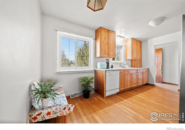 kitchen featuring white dishwasher, light brown cabinets, sink, and light hardwood / wood-style flooring