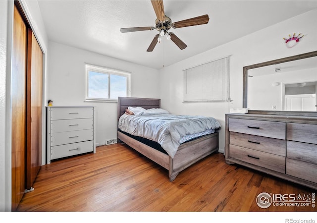 bedroom with hardwood / wood-style floors, ceiling fan, and a closet