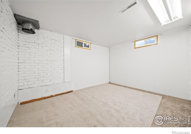 basement featuring carpet floors and brick wall