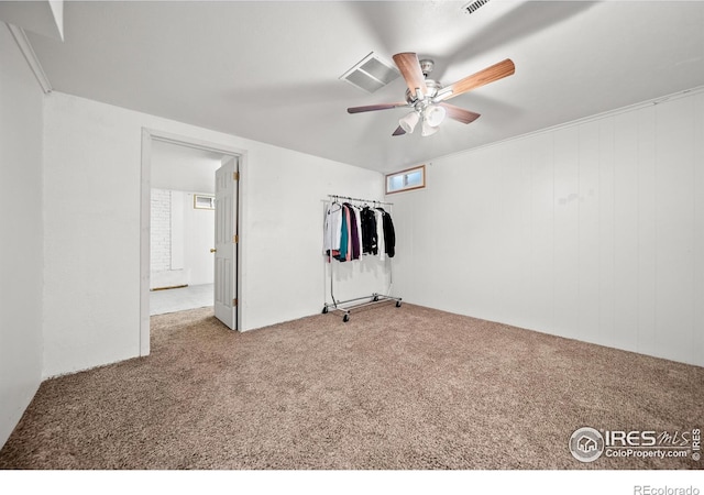 unfurnished bedroom featuring carpet flooring, ceiling fan, and wooden walls