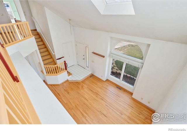 interior space with vaulted ceiling with skylight and light wood-type flooring