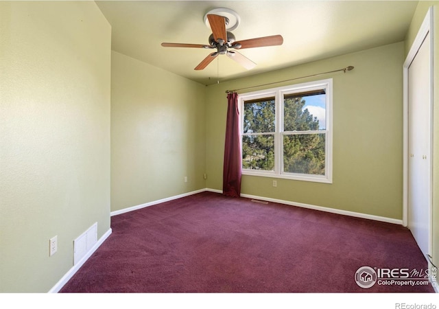 spare room featuring dark colored carpet and ceiling fan