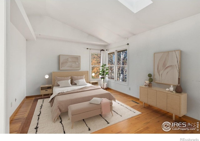 bedroom with lofted ceiling with skylight and light wood-type flooring