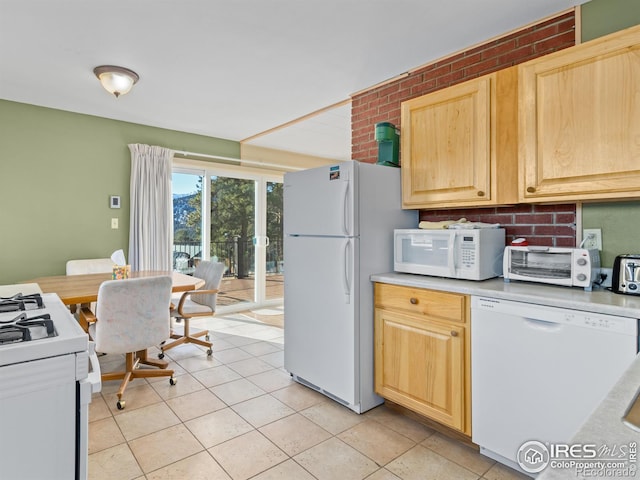 kitchen featuring light tile patterned floors, white appliances, brick wall, and light brown cabinets