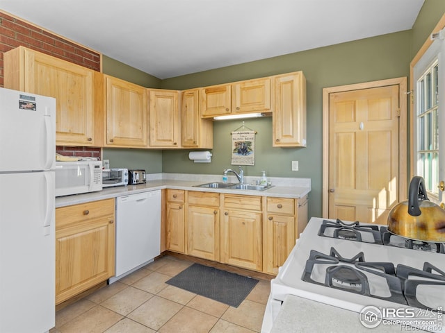 kitchen featuring sink, light tile patterned floors, light brown cabinets, white appliances, and brick wall