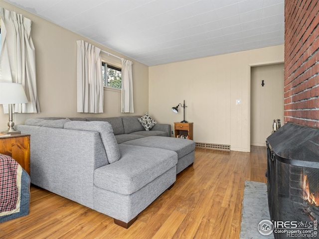 living room with light hardwood / wood-style flooring, a baseboard radiator, and a wood stove