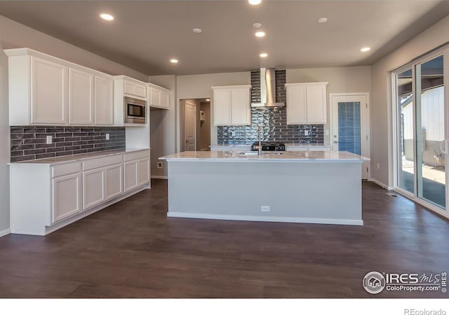 6105 Saddle Horn Dr, Timnath, CO 80547 - kitchen featuring wall chimney range hood, stainless steel microwave, backsplash, dark wood-style floors, and recessed lighting
