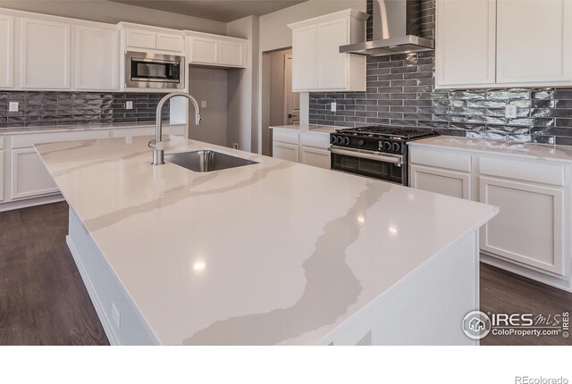 6105 Saddle Horn Dr, Timnath, CO 80547 - kitchen featuring wall chimney exhaust hood, gas stove, stainless steel microwave, a kitchen island with sink, and white cabinets