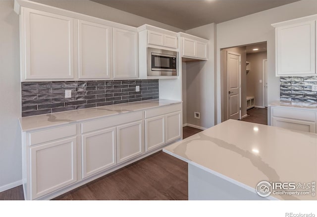 6105 Saddle Horn Dr, Timnath, CO 80547 - kitchen featuring stainless steel microwave, white cabinets, dark wood finished floors, tasteful backsplash, and recessed lighting