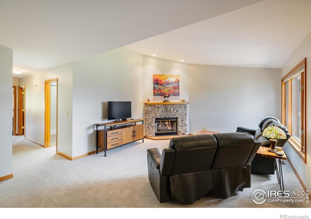 living room featuring light carpet, vaulted ceiling, and a stone fireplace