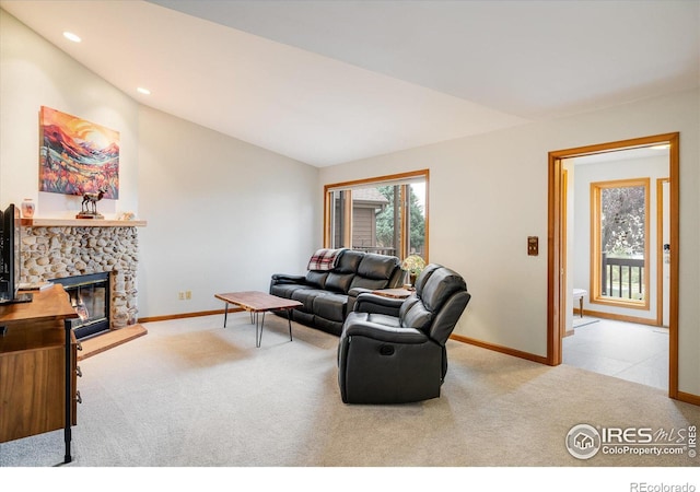 living room featuring lofted ceiling, a fireplace, and light carpet