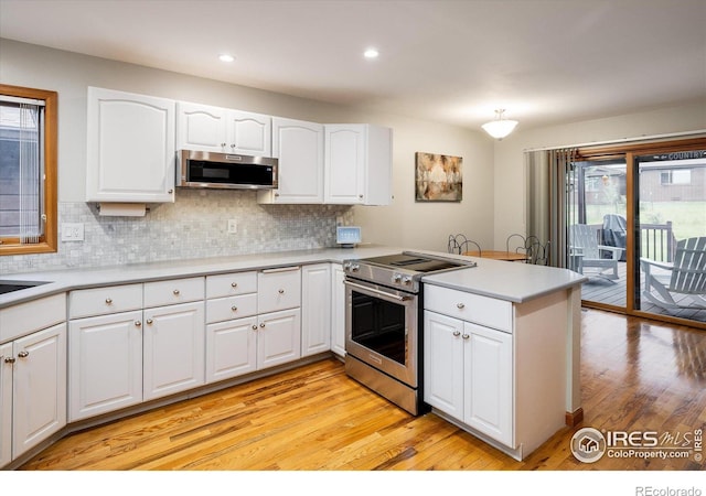 kitchen featuring kitchen peninsula, stainless steel appliances, light hardwood / wood-style flooring, and white cabinetry