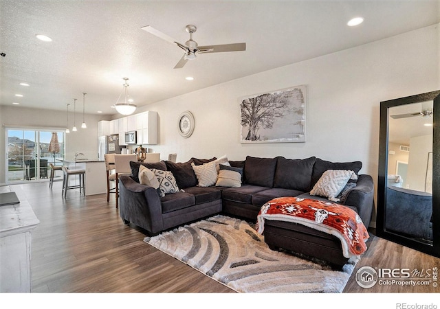 living room featuring hardwood / wood-style floors, a textured ceiling, and ceiling fan