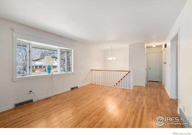 unfurnished room featuring light hardwood / wood-style flooring and a notable chandelier