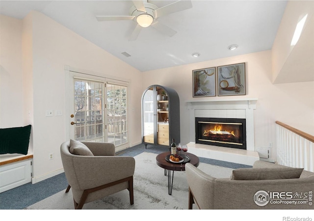 carpeted living room featuring ceiling fan, a fireplace, and vaulted ceiling