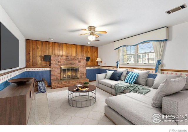 carpeted living room featuring a fireplace, ceiling fan, and wood walls