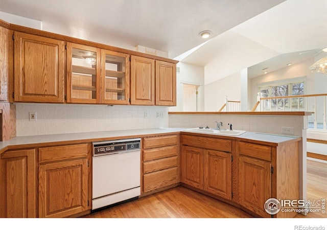 kitchen featuring sink, white dishwasher, light hardwood / wood-style floors, vaulted ceiling, and decorative backsplash