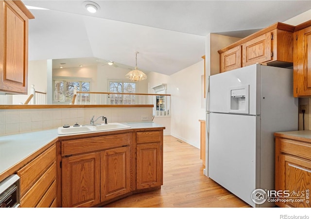 kitchen featuring light wood-type flooring, sink, decorative light fixtures, white fridge, and lofted ceiling