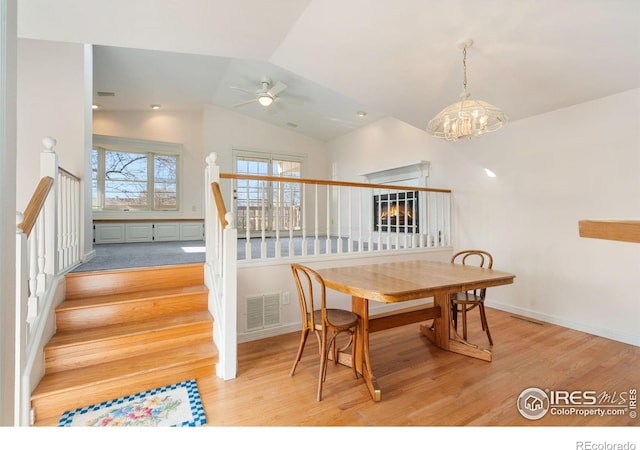 dining room featuring ceiling fan with notable chandelier, light hardwood / wood-style floors, and lofted ceiling