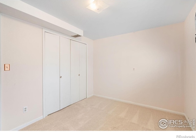 unfurnished bedroom featuring light colored carpet and a closet