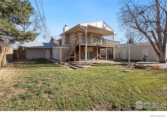 rear view of property featuring a lawn, a patio, and a wooden deck