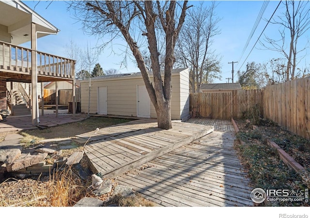 wooden terrace featuring an outbuilding and a patio