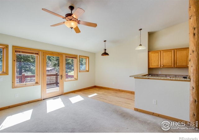 interior space featuring pendant lighting, ceiling fan, light wood-type flooring, and vaulted ceiling