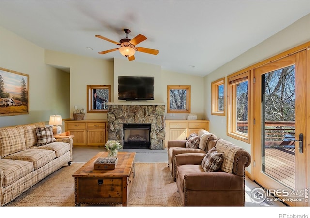 carpeted living room featuring a fireplace, vaulted ceiling, and ceiling fan