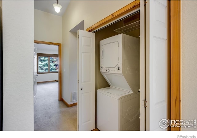 laundry room featuring light carpet and stacked washer and clothes dryer