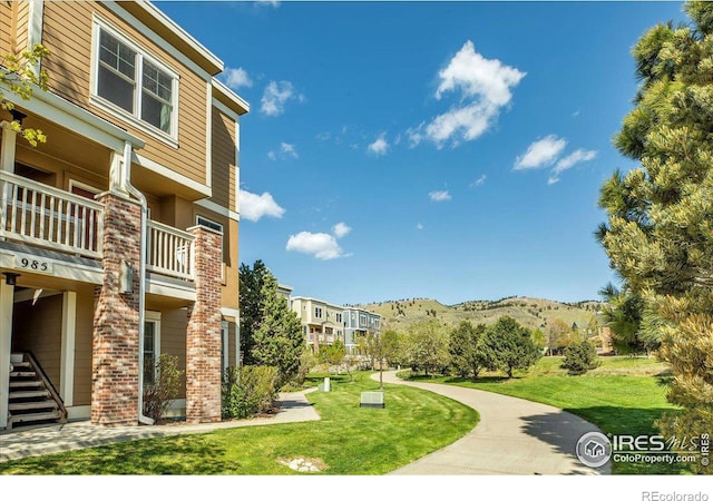 view of home's community with a mountain view and a yard