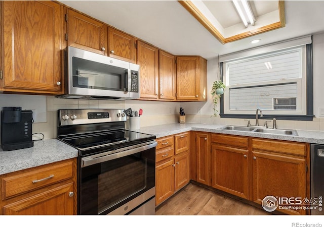 kitchen with light wood-type flooring, sink, appliances with stainless steel finishes, and tasteful backsplash