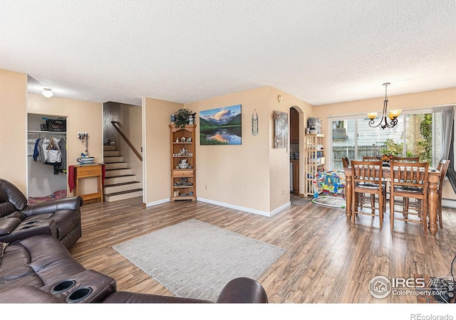 living room featuring arched walkways, wood finished floors, a textured ceiling, and stairs