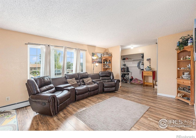 living room with a baseboard heating unit, a textured ceiling, baseboards, and wood finished floors