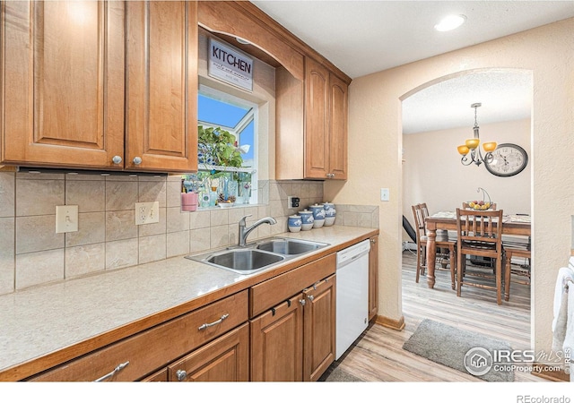 kitchen featuring light countertops, backsplash, brown cabinetry, a sink, and dishwasher