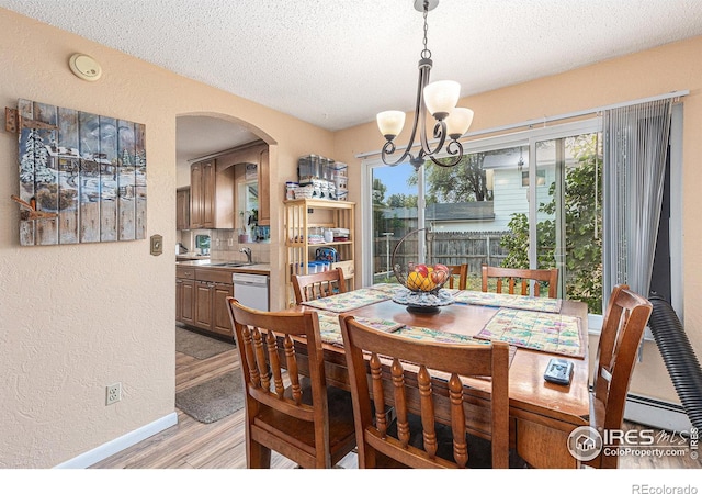 dining space featuring a healthy amount of sunlight, light wood finished floors, and a textured wall