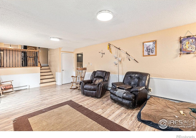 sitting room with a baseboard radiator, stairway, a textured ceiling, and wood finished floors