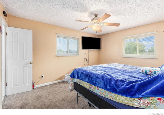 carpeted bedroom with multiple windows, ceiling fan, a textured ceiling, and baseboards