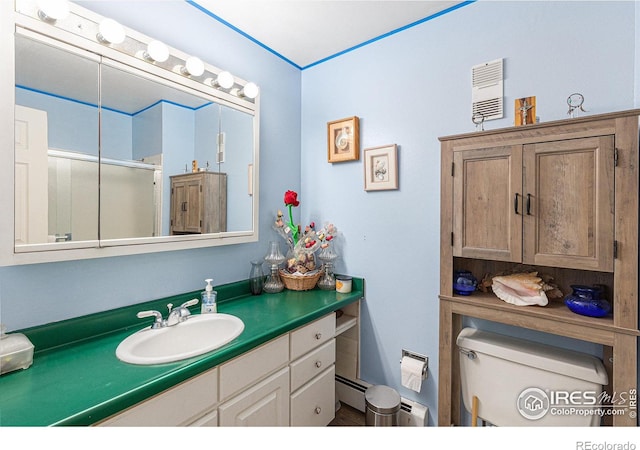 full bathroom featuring toilet, a baseboard heating unit, a shower with shower door, and vanity