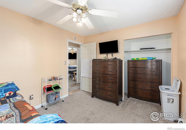 carpeted bedroom with a textured ceiling, a ceiling fan, and baseboards