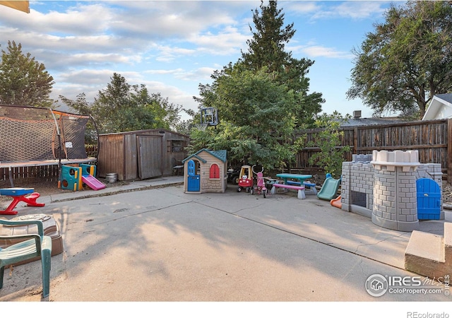 view of patio featuring a storage shed, a trampoline, an outbuilding, and fence