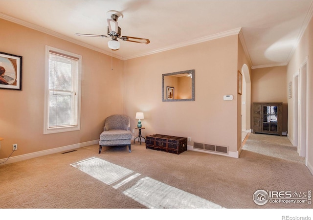 living area with ceiling fan, light colored carpet, and ornamental molding