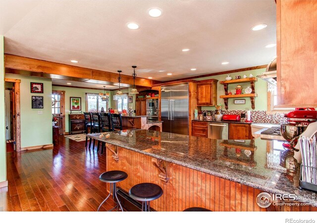 580 Saddle Notch Rd, Loveland, CO 80537 - kitchen with stainless steel appliances, a peninsula, recessed lighting, dark wood-style floors, and brown cabinets
