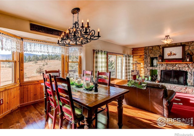 580 Saddle Notch Rd, Loveland, CO 80537 - dining area featuring hardwood / wood-style flooring, a chandelier, a fireplace, wood walls, and a wainscoted wall