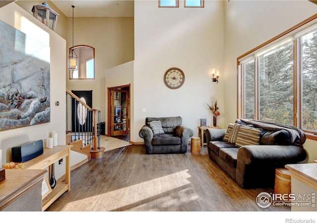 living room with light wood-type flooring and a towering ceiling