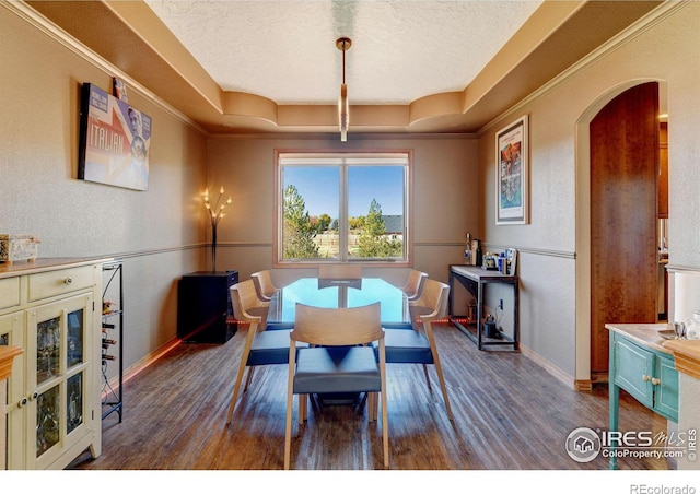 dining area featuring dark hardwood / wood-style flooring, ornamental molding, and a tray ceiling