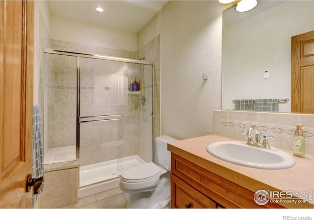 bathroom with tile patterned floors, toilet, vanity, and walk in shower